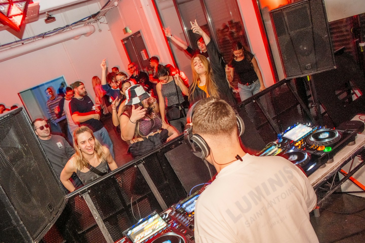 DJ performs music for a crowd dancing at a party.